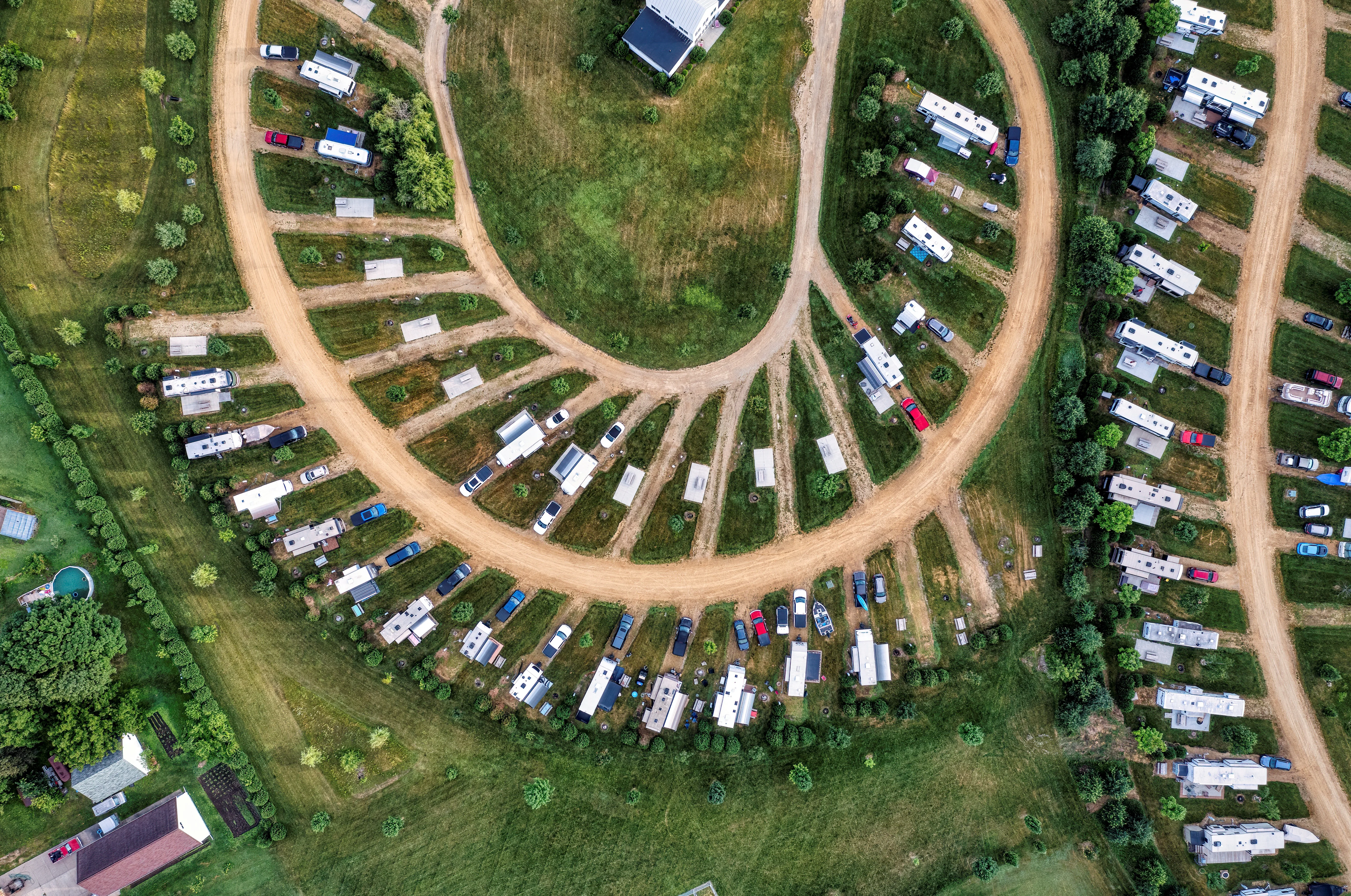 bird view on trailers with cars and trucks by a dirt road with a nice bend resulting in an organic pattern