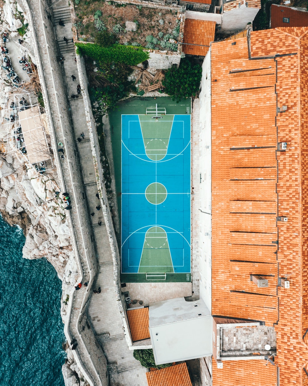 Backyard playing field in between a house, a pathway and the water